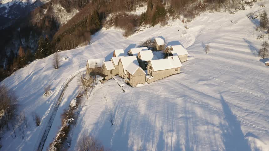 A village with houses covered in snow with a mountain range sky and clouds in the background