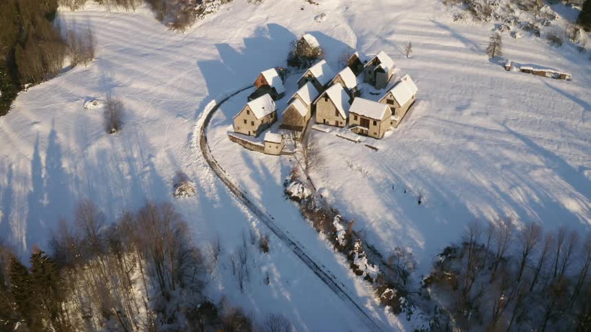 A tightly bunched group of buildings on a snowy mountain slope during the day