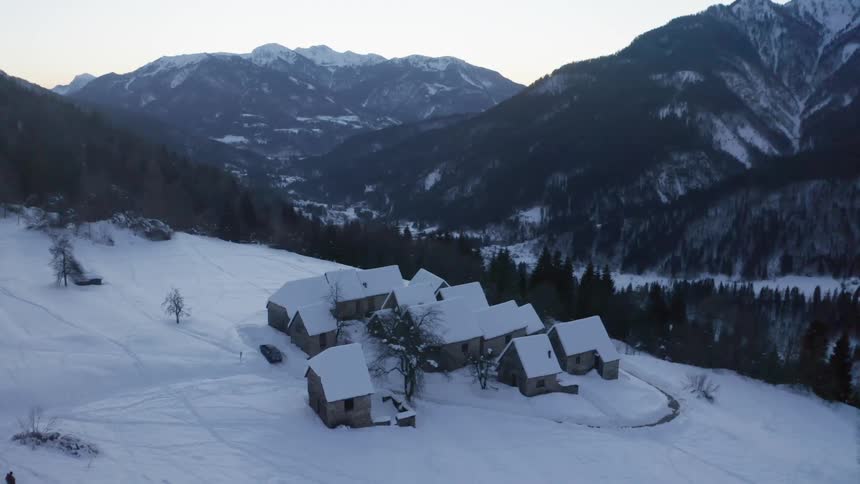 A group of houses of a the slope of a mountain covered in snow during the day