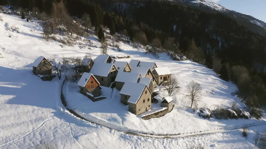 An aerial view of a small mountain village in snowy mountains on a winter day