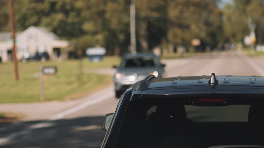 Cars are driving on a street in a neighborhood in spring