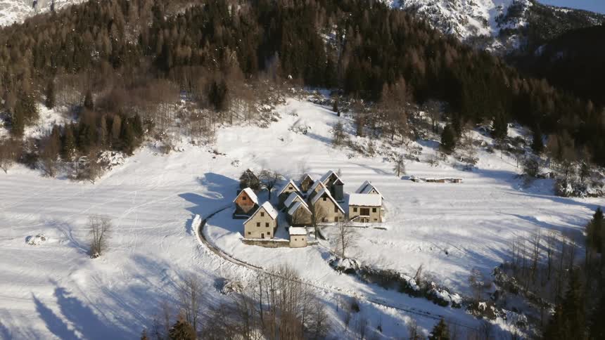 A group of houses on the snowy slope of a mountain on a sunny day