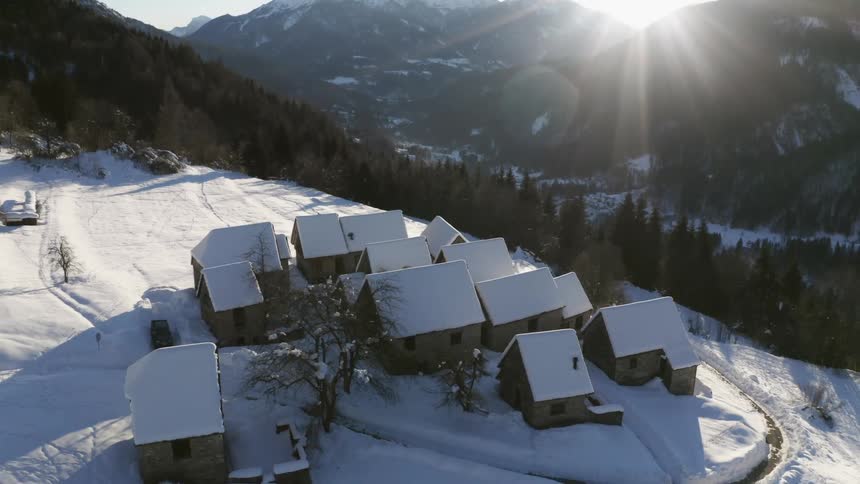 Buildings sit on a snow covered field in a rural area