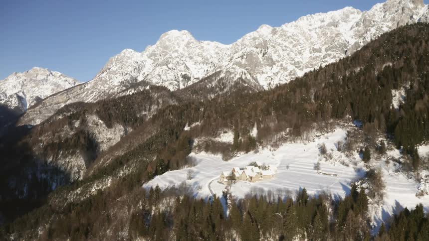 An aerial shot of a house in a snowy forest