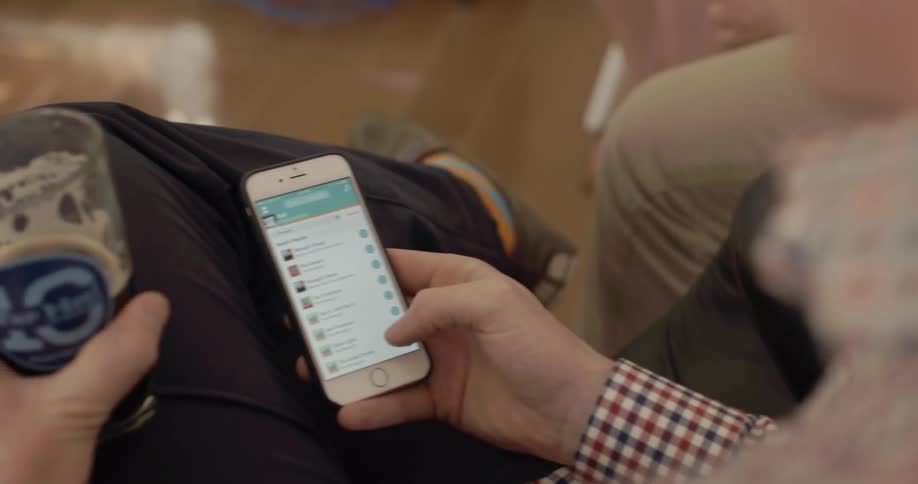 A person is checking their phone with a rink in their other hand