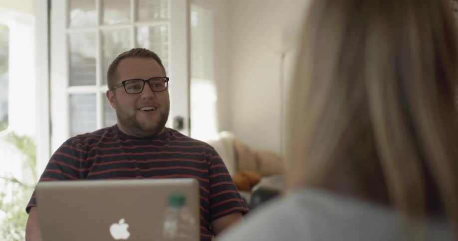 A man laughing and smiling as he chats with a woman