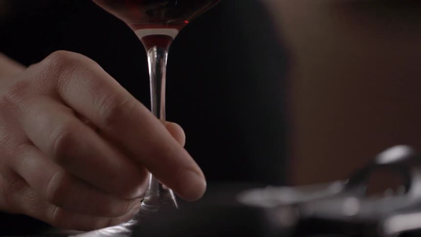 A person is moving a wine glass along a table