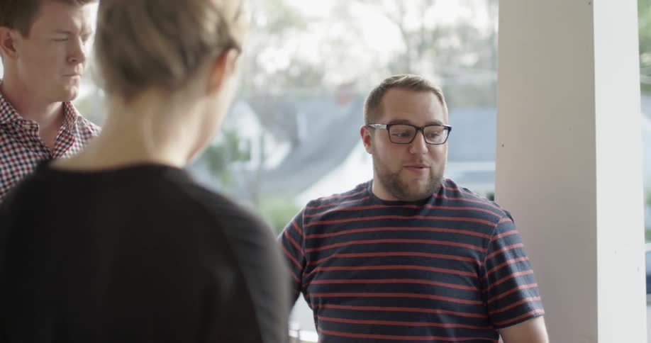 A group of people chat outside on a porch