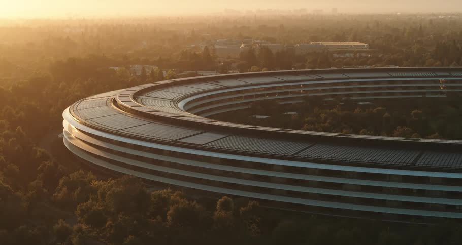 Futuristic modern round building surrounded by trees with a bright sun and mountains on the horizon