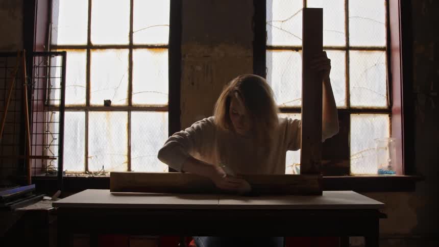 A woman is painting lines on a wooden board
