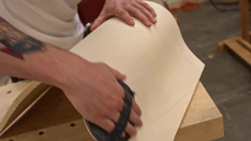A man is sanding a piece of wood