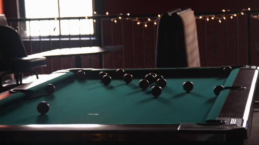 A man is shooting pool with a stick