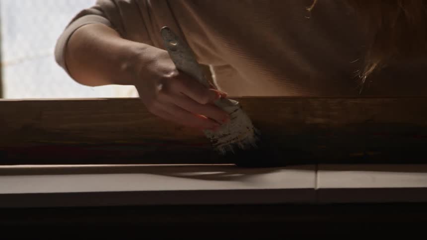 A person is painting a wooden board