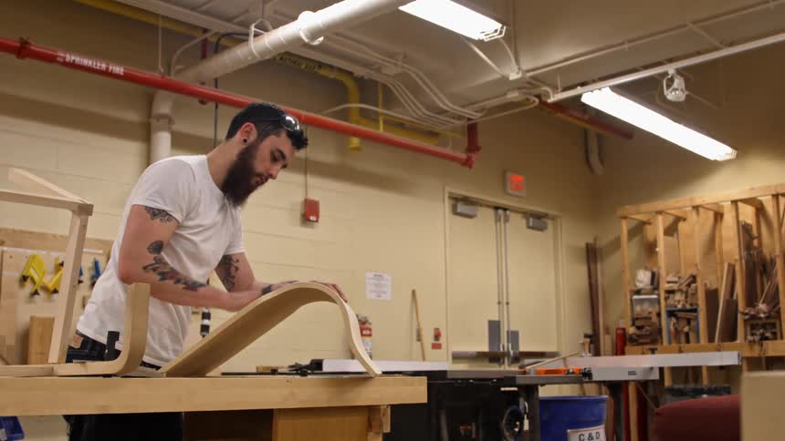 A man sands a curved piece of wood
