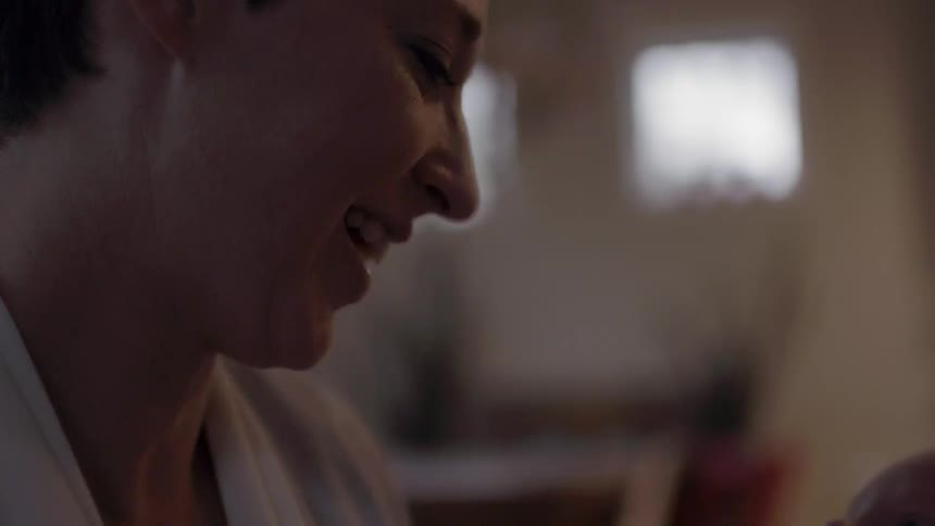 Smiling woman gently rocking her infant as she looks down at them