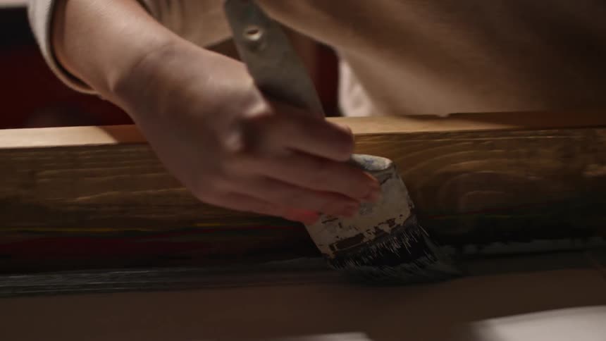 A woman using a board as a guide while painting