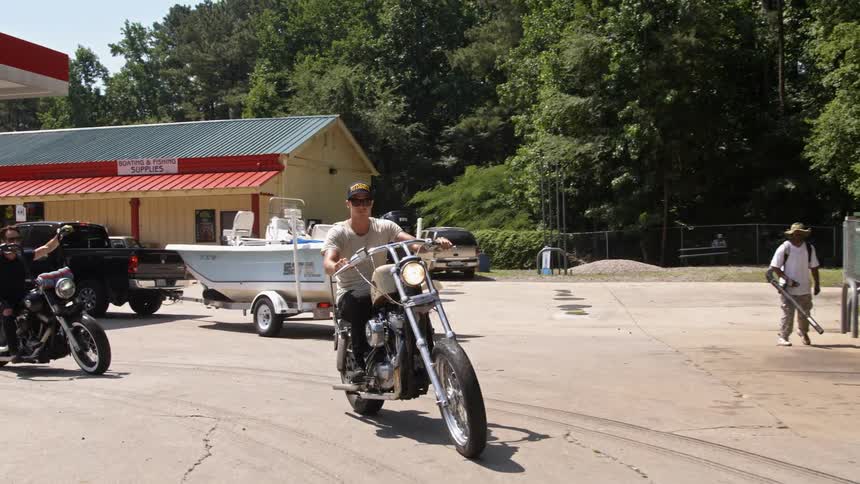 People ride motorcycles away from a gas station