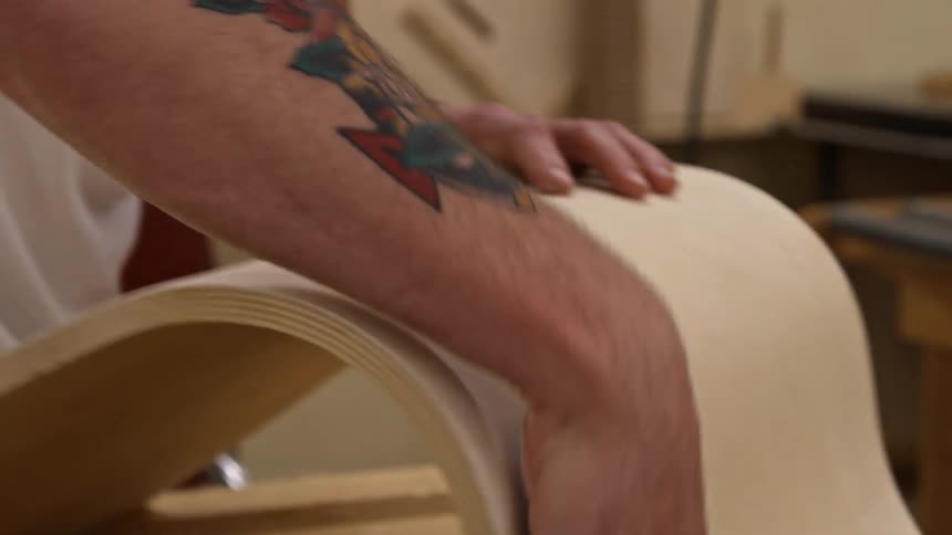 A man uses a tool to smooth wood