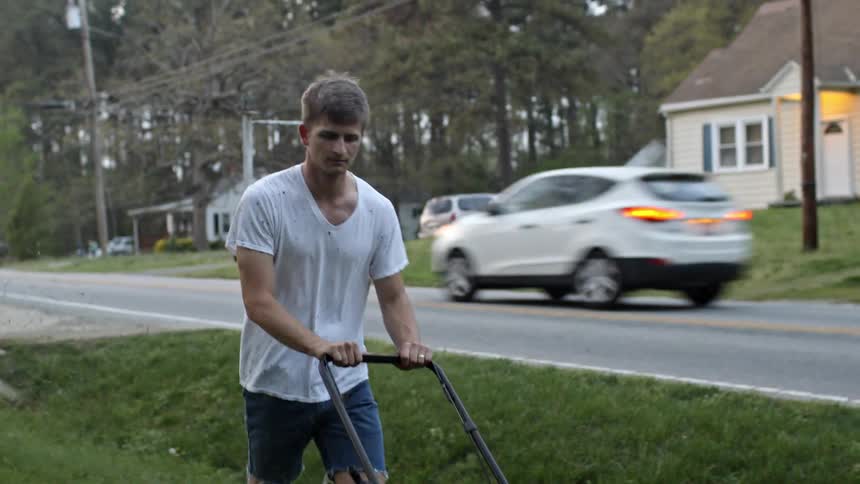 A man mows a lawn in a rural area