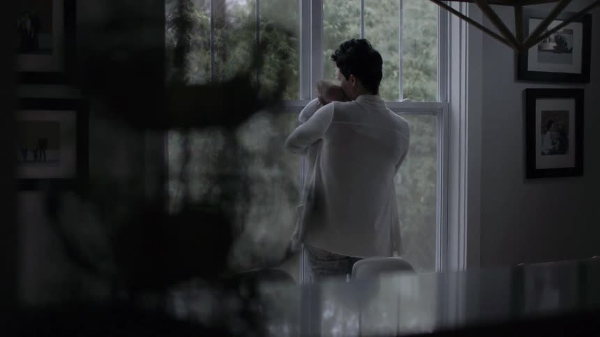 A woman is rocking a baby in her arms by a window