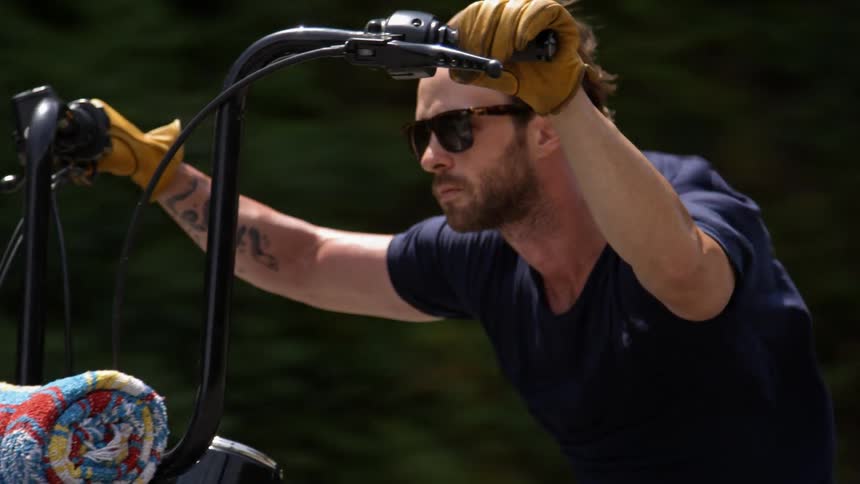A man riding a motorcycle is wearing sunglasses