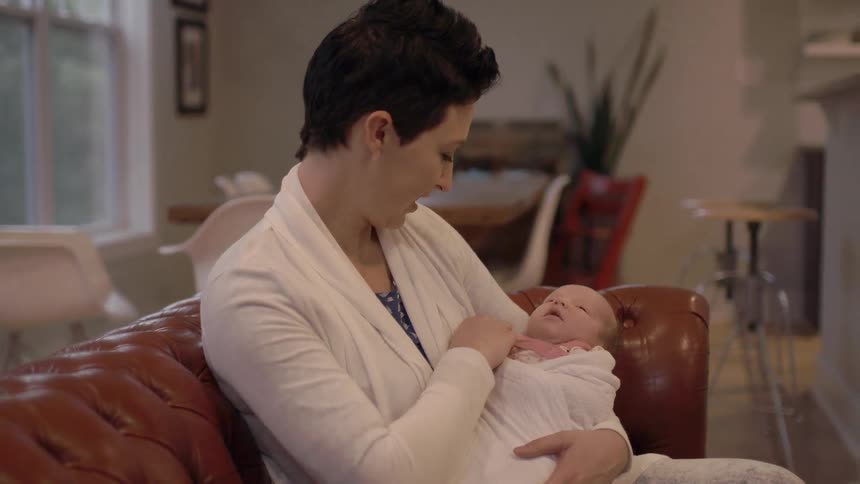 Woman sitting on a couch owning an infant