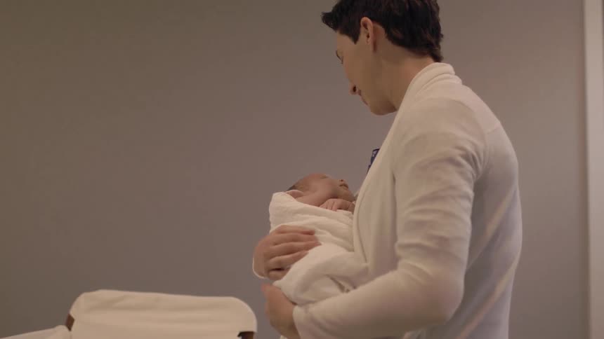 A woman speaking to a baby she is holding in her arms