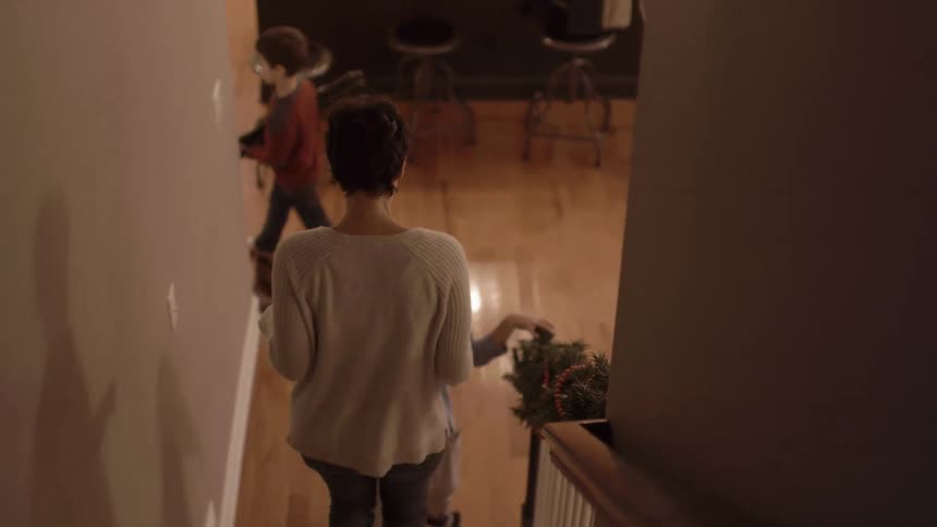 A woman and children descend steps in a home