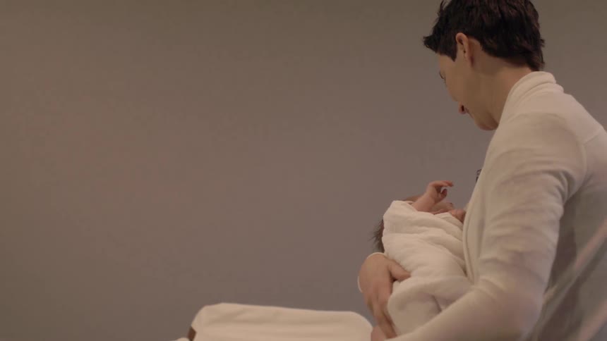 A woman lifts a newborn from a cradle