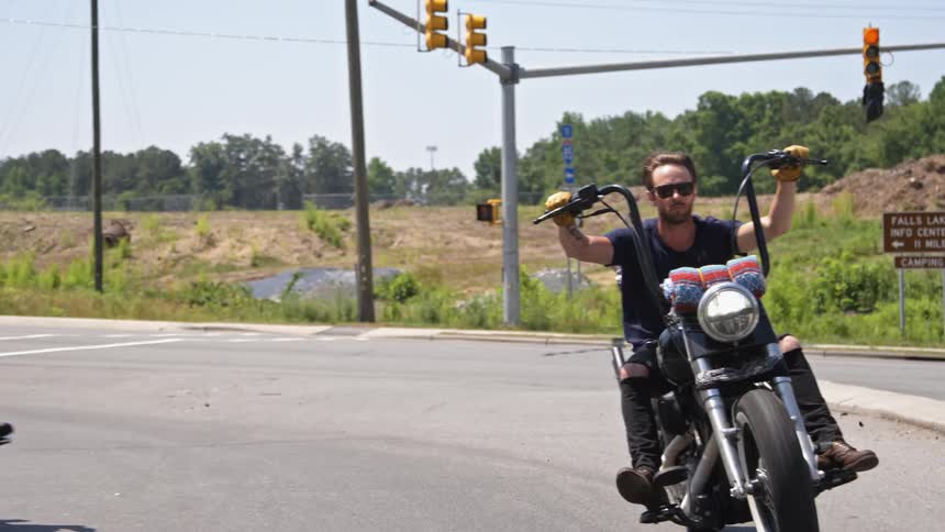 Motorcyclists ride on a town street on a sunny day