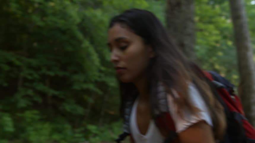A woman is hiking in a forest looking around