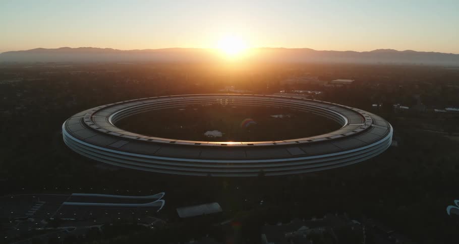 An aerial view of the sun setting behind an arena