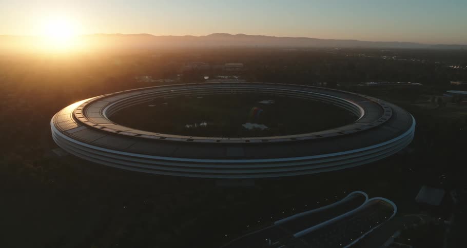 An aerial camera revolves a round a stadium in a city at dawn