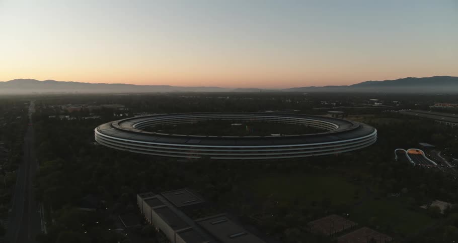 A large ring shaped building beside a road in a rural area in the evening