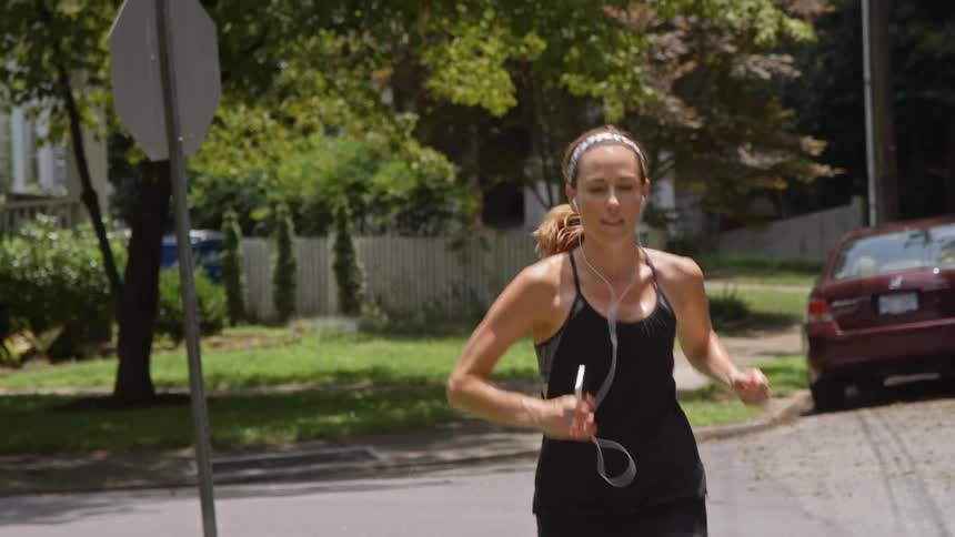 A woman is jogging on a neighborhood street