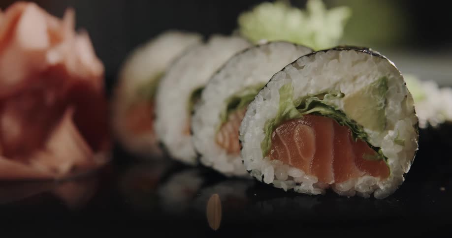 A person wearing gloves is putting sushi on a table