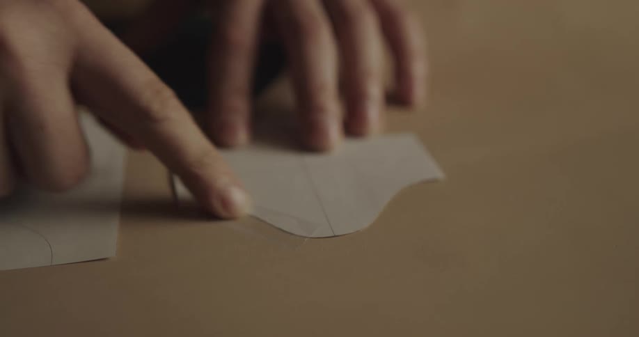 A woman tapes a piece of paper cut in to a shape on to another piece of paper