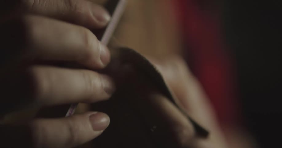 A person shaving leather with a file