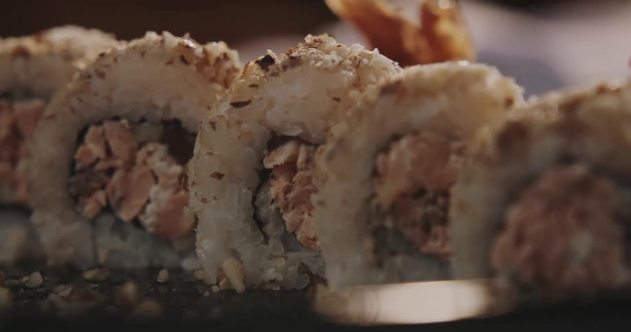 Rice rolls sit in row on brown clay dish