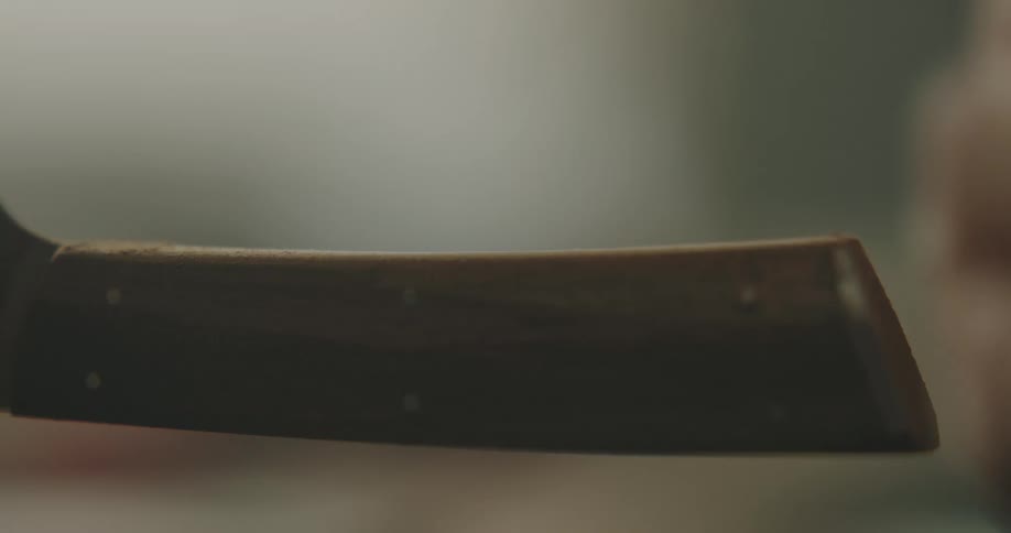 A person sands the handle of a knife