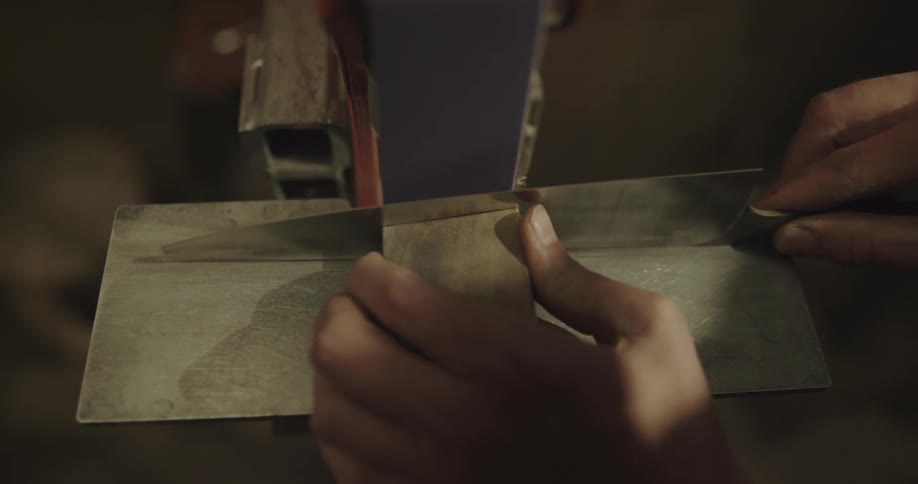 A person in a room sharpening a knife
