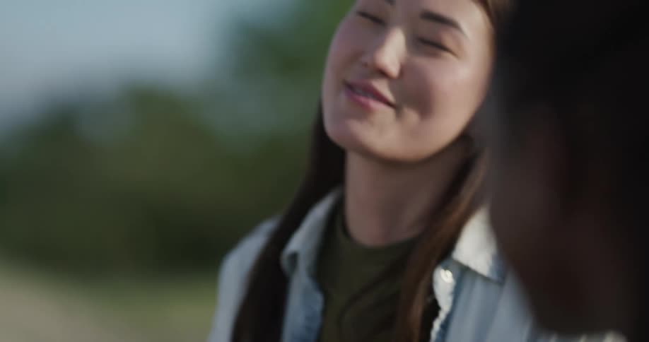 A woman holds a green beer while laughing with a friend during a picnic