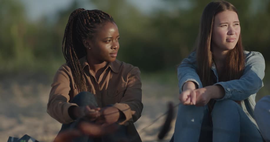 Two girls are sitting outdoors near a bonfire in spring