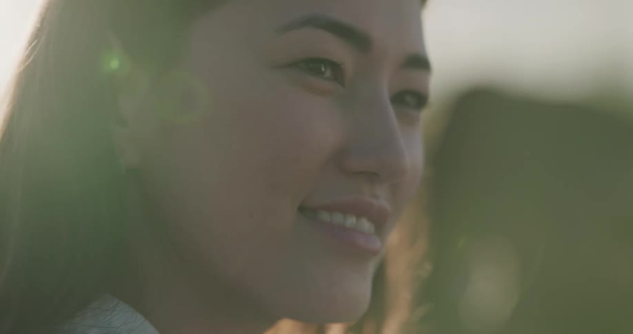 A woman is smiling outdoors at dusk