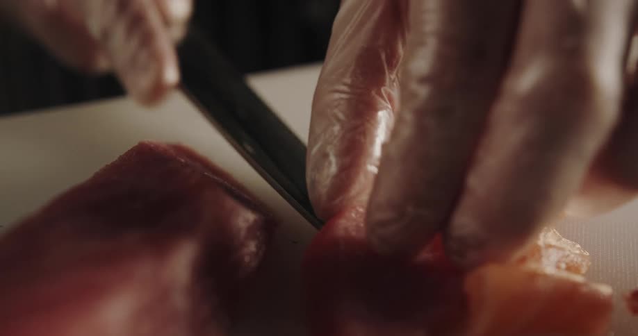 A person slicing fish on a cutting board