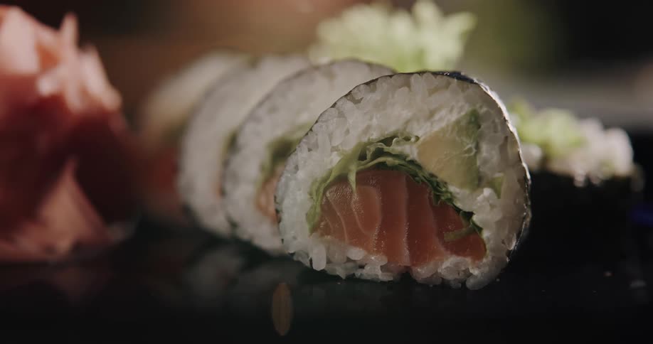 Rolled up sushi sits on top of a table along with some flowers