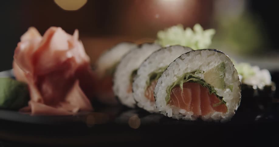 A plated and sliced salmon sushi roll with pickled ginger and wasabi