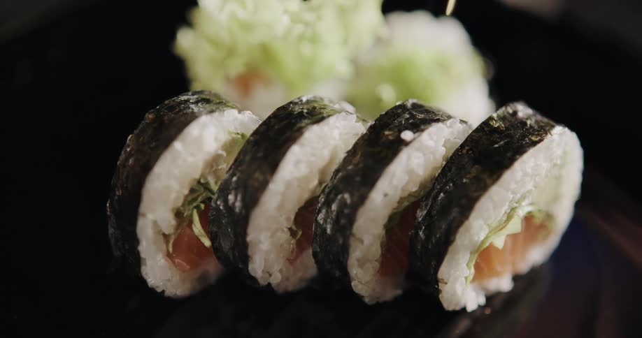 A person putting sushi and veggies on a plate