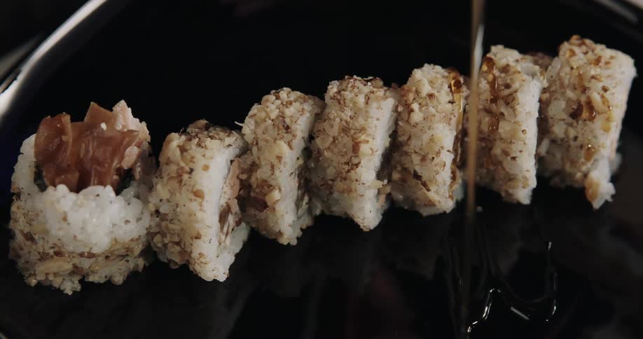 Person plates sliced sushi roll onto black plate