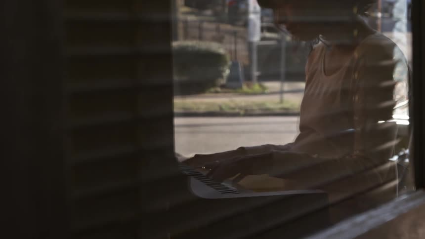 Reflection on glass of a woman playing a piano